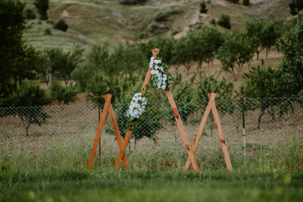 Wooden arch adorned with white flowers outdoors, ideal for weddings.